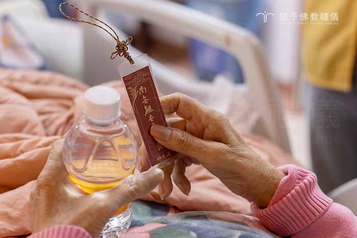 遞上佛光山甘露水與親手製作的聖號小卡，卡片上印著「南無觀世音菩薩」，為病友與佛菩薩結下一份清淨法緣 。｜楊子佛教禮儀公司